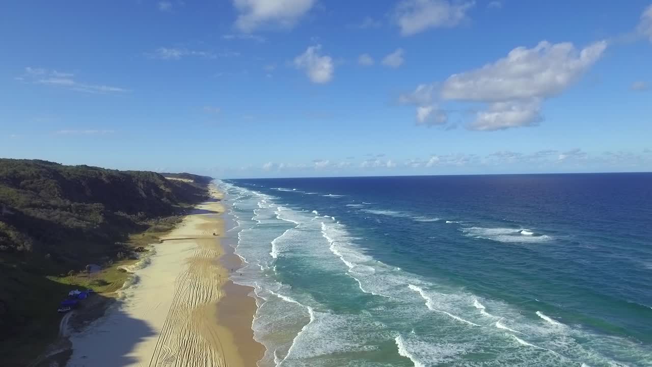 프레이저 섬의 해안을 따라 펼쳐지는 장엄한 공중 전망, 늦은 오후 그림자가 멀리 있는 사륜구동으로 해변을 가로질러 길어짐
