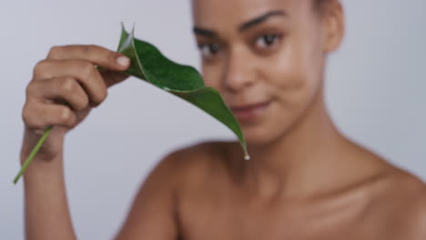 retrato de una hermosa mujer joven sosteniendo una hoja goteando agua disfrutando de un cuidado de la piel saludable mujer feliz con una piel natural suave sonriendo sobre un fondo blanco concepto de belleza