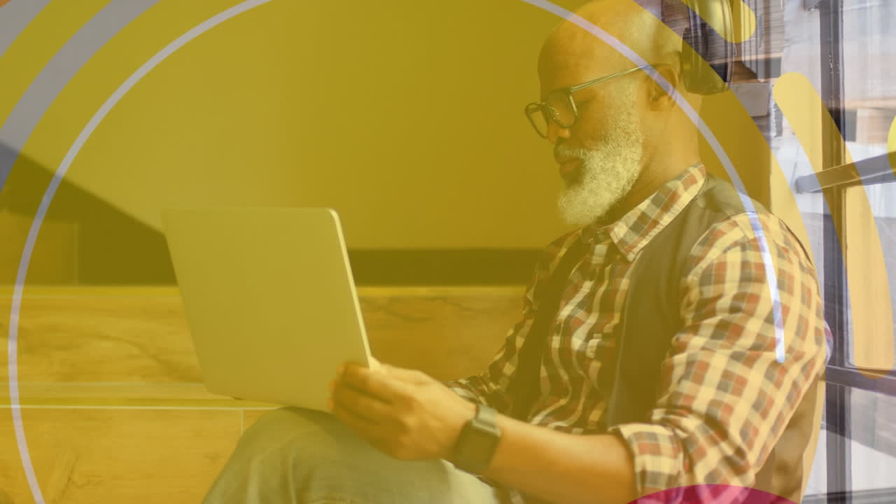 animación de formas sobre un hombre de negocios afroamericano usando una computadora portátil