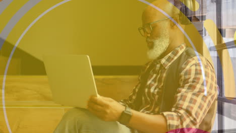 animación de formas sobre un hombre de negocios afroamericano usando una computadora portátil