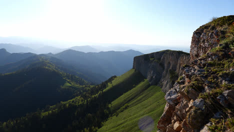 pan across gentle grass and pine tree forest slope with exposed rocky cliff, kavkaz mountain