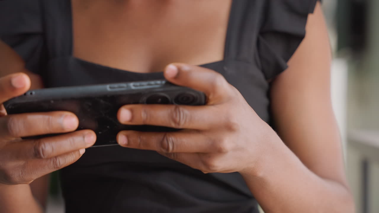 Zwarte vrouw sms't op mobiele telefoon, close-up toont bovenlichaam en handen in zwarte jurk, vingers scrollen door berichten, zacht avondlicht, intieme romantische sfeer, subtiele anticipatie en verbinding