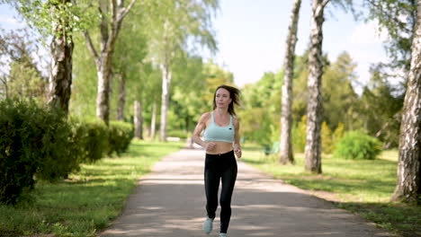 smiling sportswoman running at the park in a sunny day