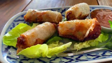 Rollitos-De-Primavera-Tradicionales-Sobre-Lechuga-Con-Salsa-De-Chile-Dulce-En-Un-Restaurante-Tailandés,-Comida-Asiática,-Entrante-Para-El-Almuerzo,-Toma-De-4k