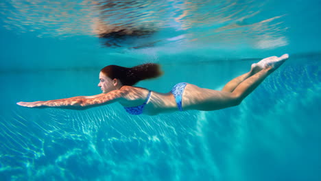 young woman swimming underwater in a pool