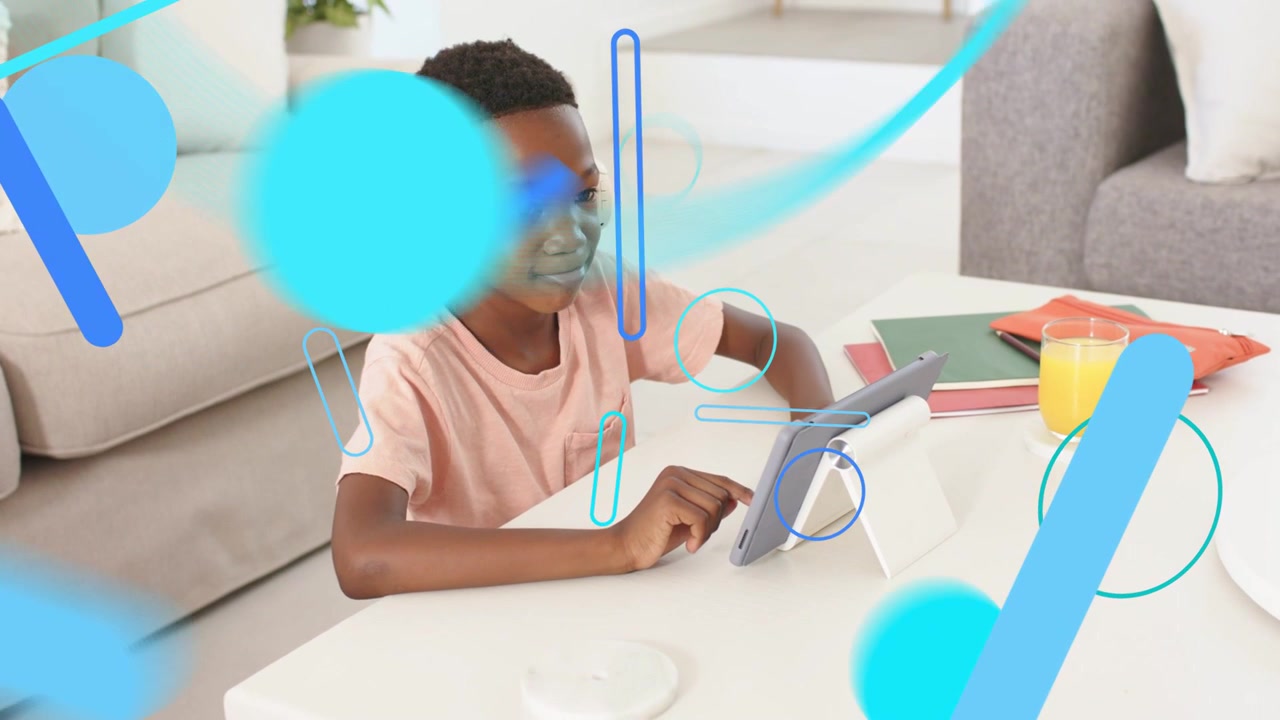 Male student tapping tablet at low table, starting blue shapes growing then fading for education