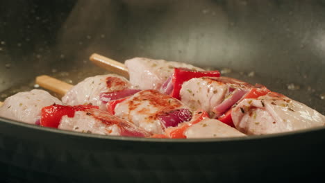 cooking pork skewers in a pan