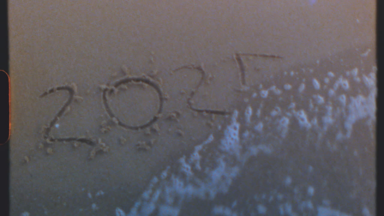2024 y 2025 escritos en la arena de una playa