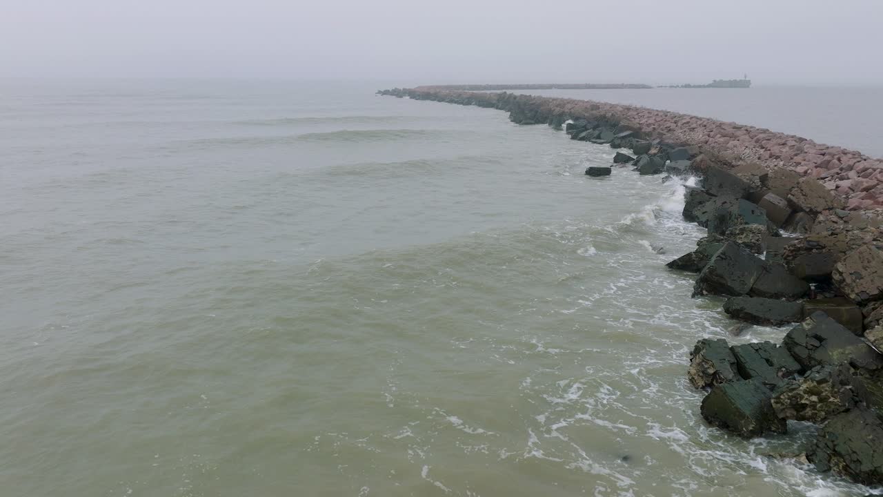 리파자 돌 부두 항구, 발트해 해안선, 짙은 안개가 낀 안개 낀 날, 변덕스러운 느낌, 큰 폭풍이 튀는 것, 뒤로 움직이는 넓은 드론 샷