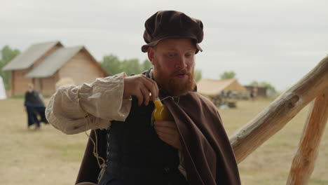 un hombre con ropa medieval abre una botella de poción mágica.