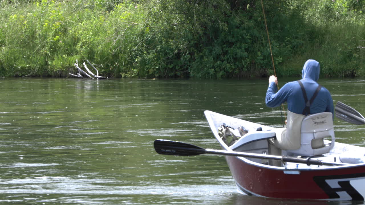Two friends fishing on small boat on Snake River, Idaho. Static shot.