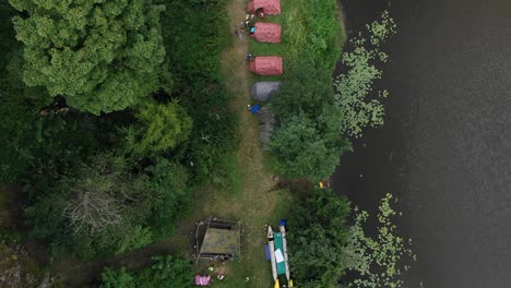 Vista-Aérea-A-Vista-De-Pájaro-De-Personas-Acampando-En-Tiendas-De-Campaña-En-El-Bosque-A-Lo-Largo-De-Un-Río