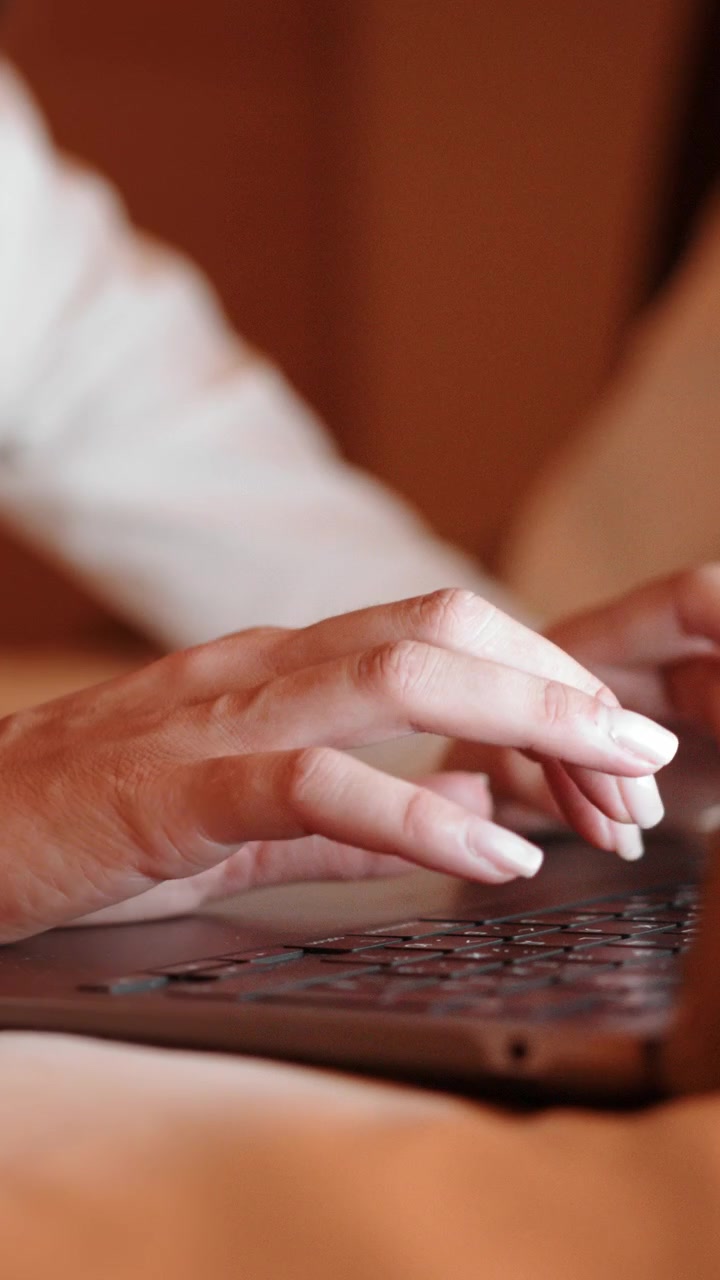 Un primo piano delle mani di una persona che digitano su una tastiera di laptop, con un focus sulle mani e sulla tastiera