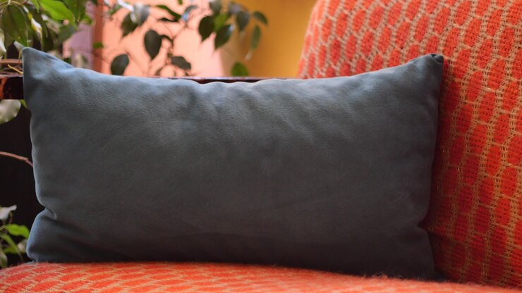 Close-up of a Grey Pillow on an Orange Textured Couch