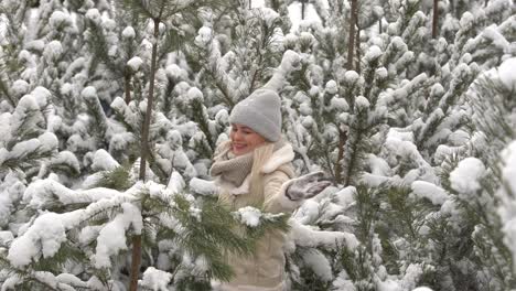 a girl in white clothes stands near a pine tree in the snow.