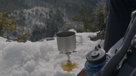 a man boiling water in a winter mountain