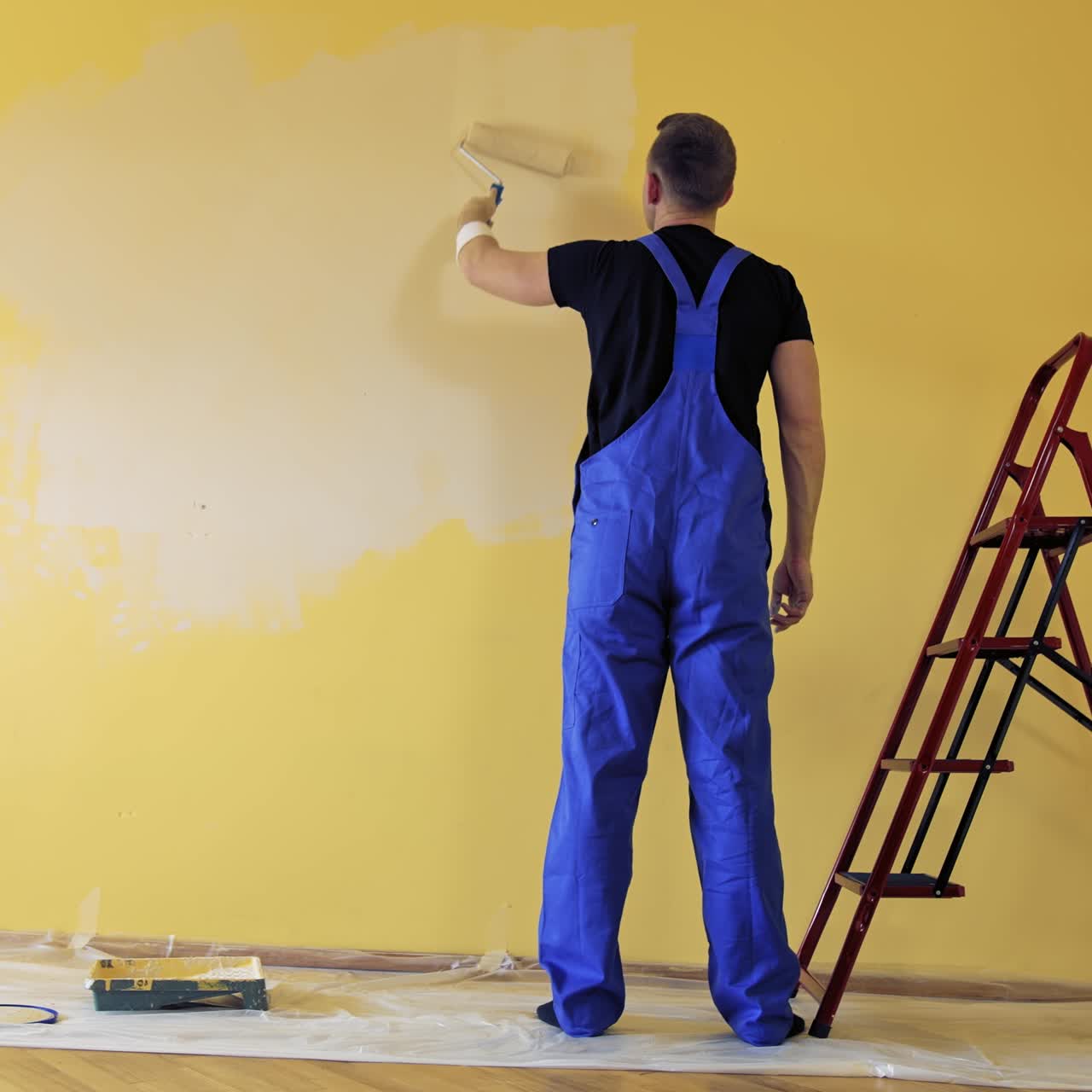 Painter paints on yellow wall. Repair, building and home concept