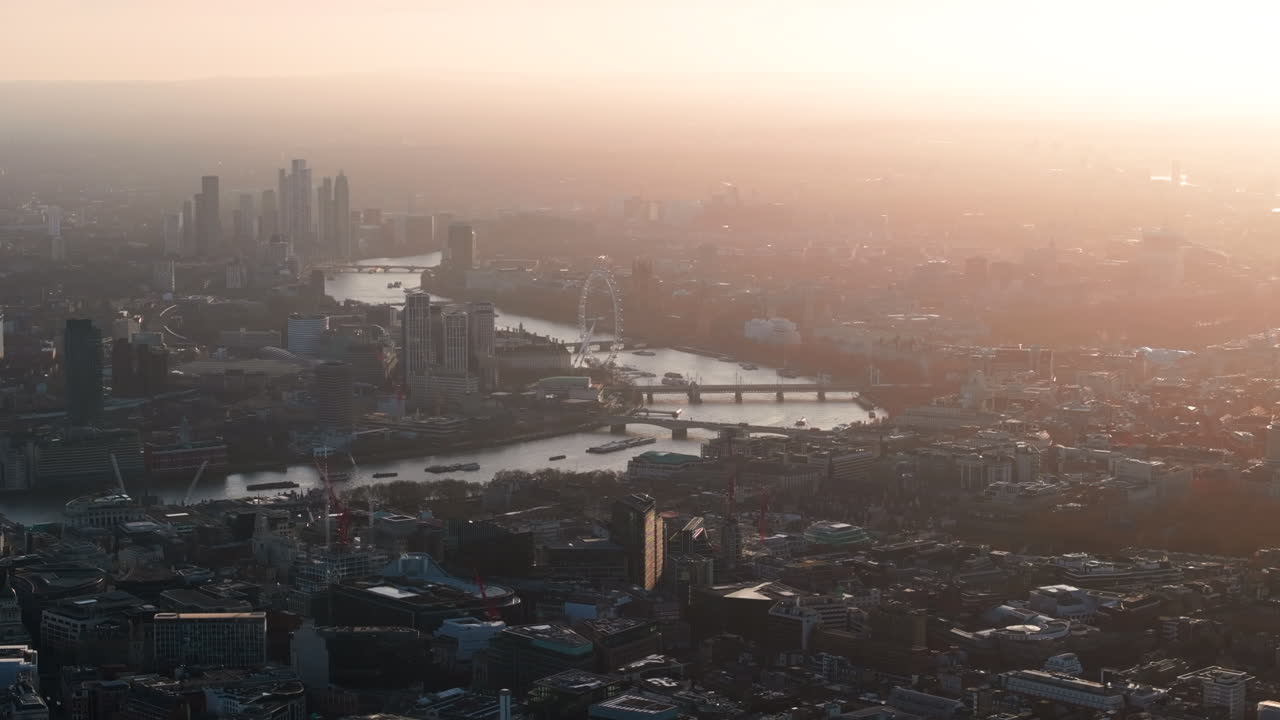 런던 아이 (london eye) 와 해가 지는 테임즈 강의 의회 건물을 바라보는 긴밀한 공중 촬영