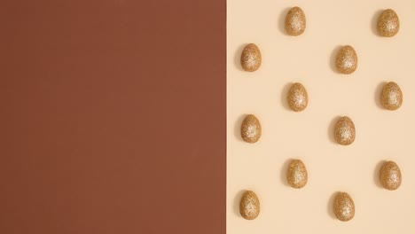 creative easter pattern with golden glitter eggs rotating on nude brown background. stop motion