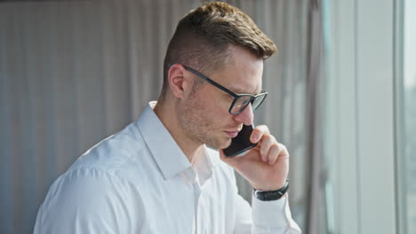 man in white shirt speaking on the phone looking worried. businessman concerned having phone conversation.