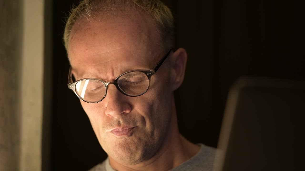 hombre escandinavo maduro con gafas pensando mientras usa la computadora portátil