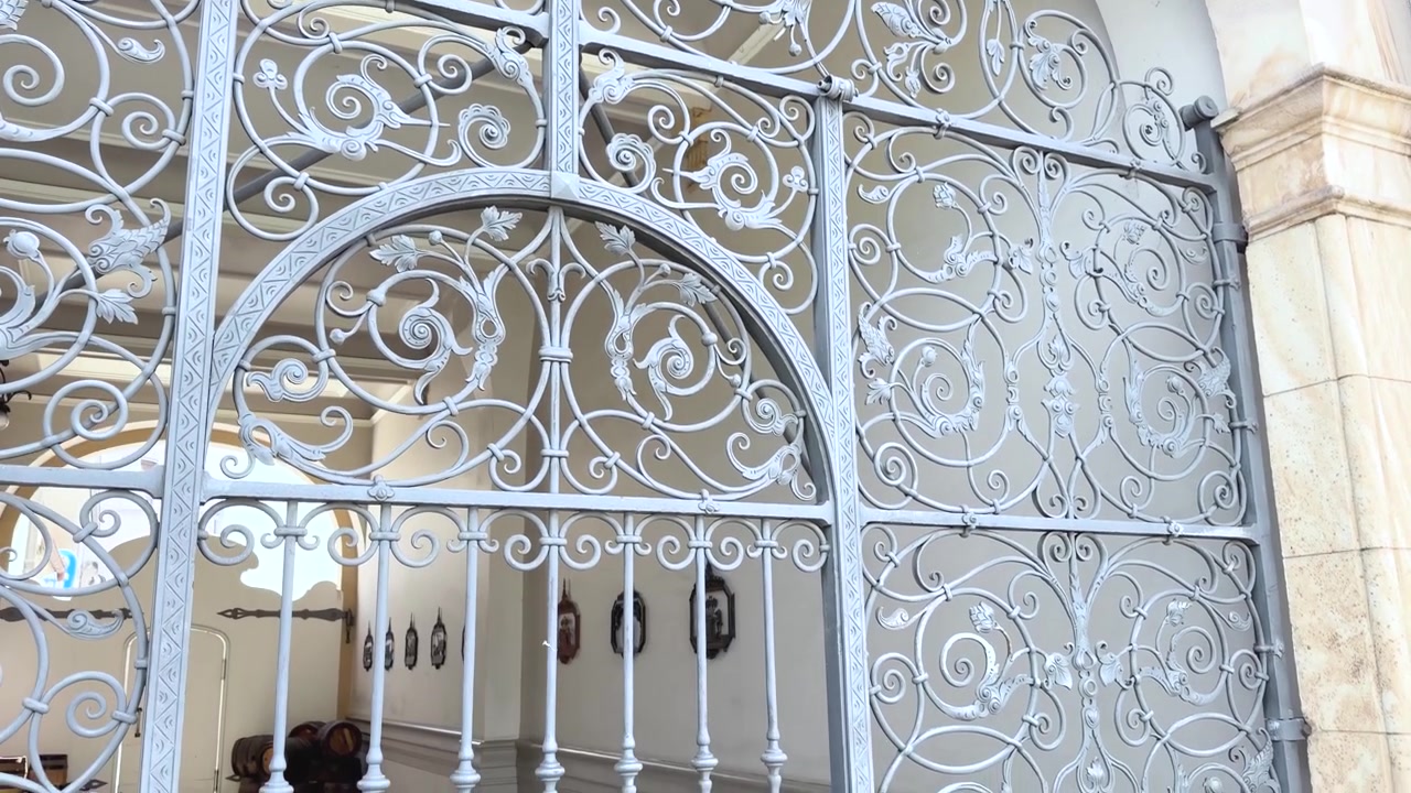 Un elegante cancello in ferro battuto con intarsi elaborati incornicia l'ingresso di un cortile storico a Lörrach, Germania. Inclinazione lenta verso il basso ripresa da vicino.