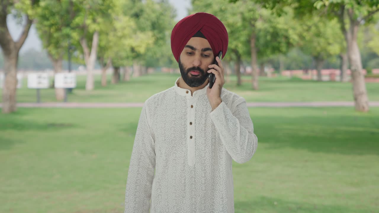 Uomo indiano Sikh che parla al telefono in un parco