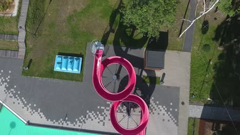 aerial shot of a girl riding on water slide to the swimming pool