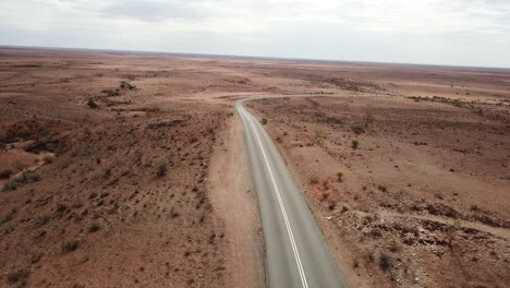 aerial: drone shot following a deserted highway winding through a post apocalyptic looking environment, near broken hill australia