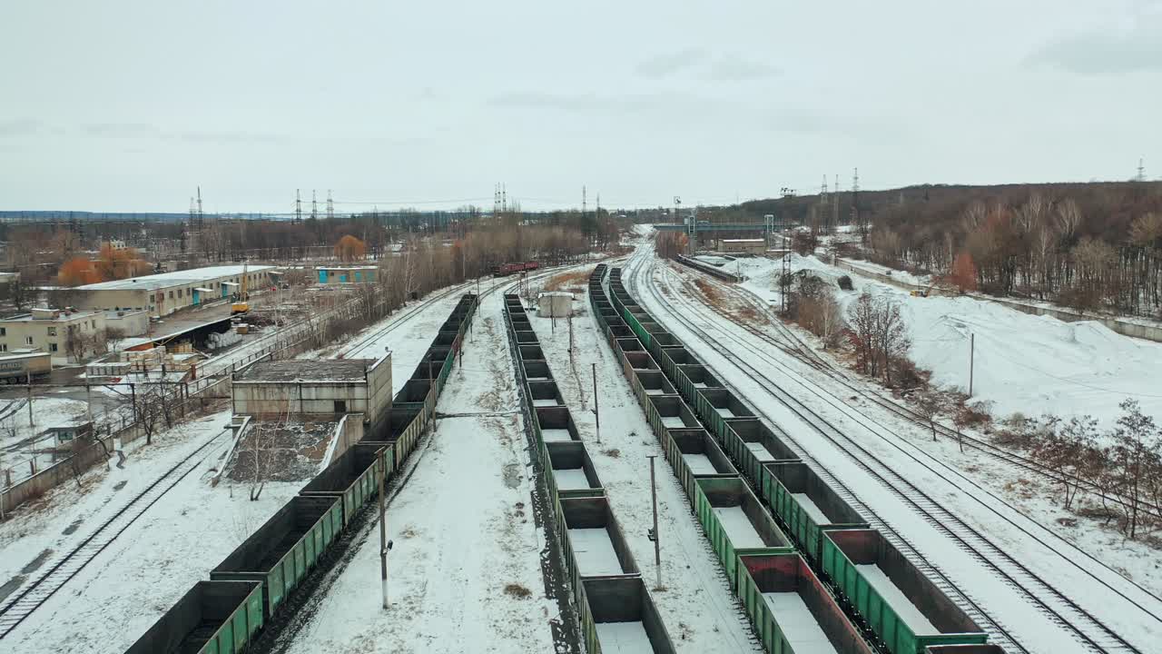 Long rows of containers stand on rails on the territory of the railway. Shipping. Camera motion to back. Aerial view.