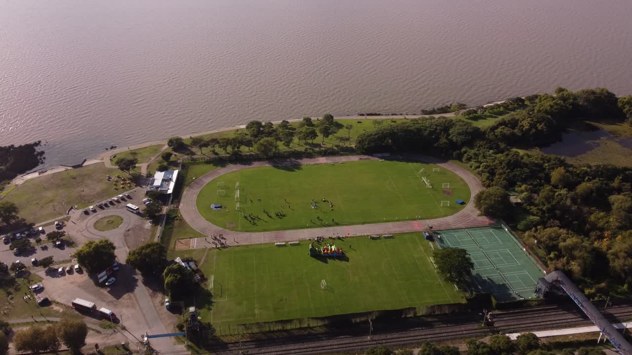 Ludzie trenujący na nadbrzeżnym boisku piłkarskim przed rzeką Rio de la Plata w Buenos Aires, Argentyna