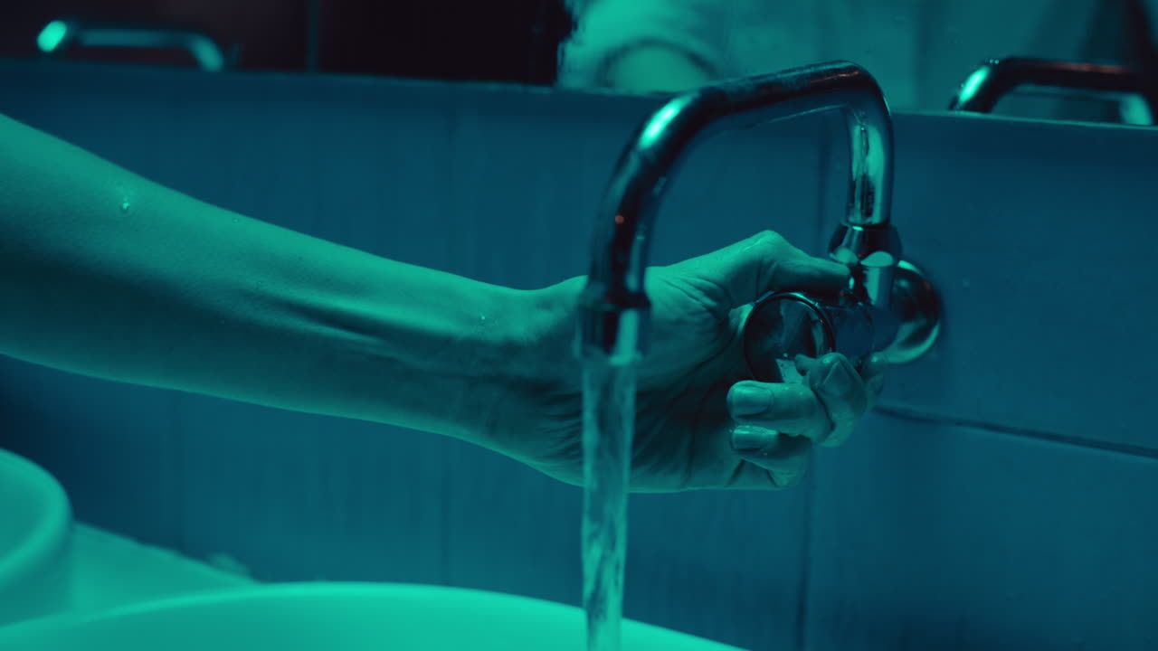 Washing Hands in a Teal-Lit Bathroom