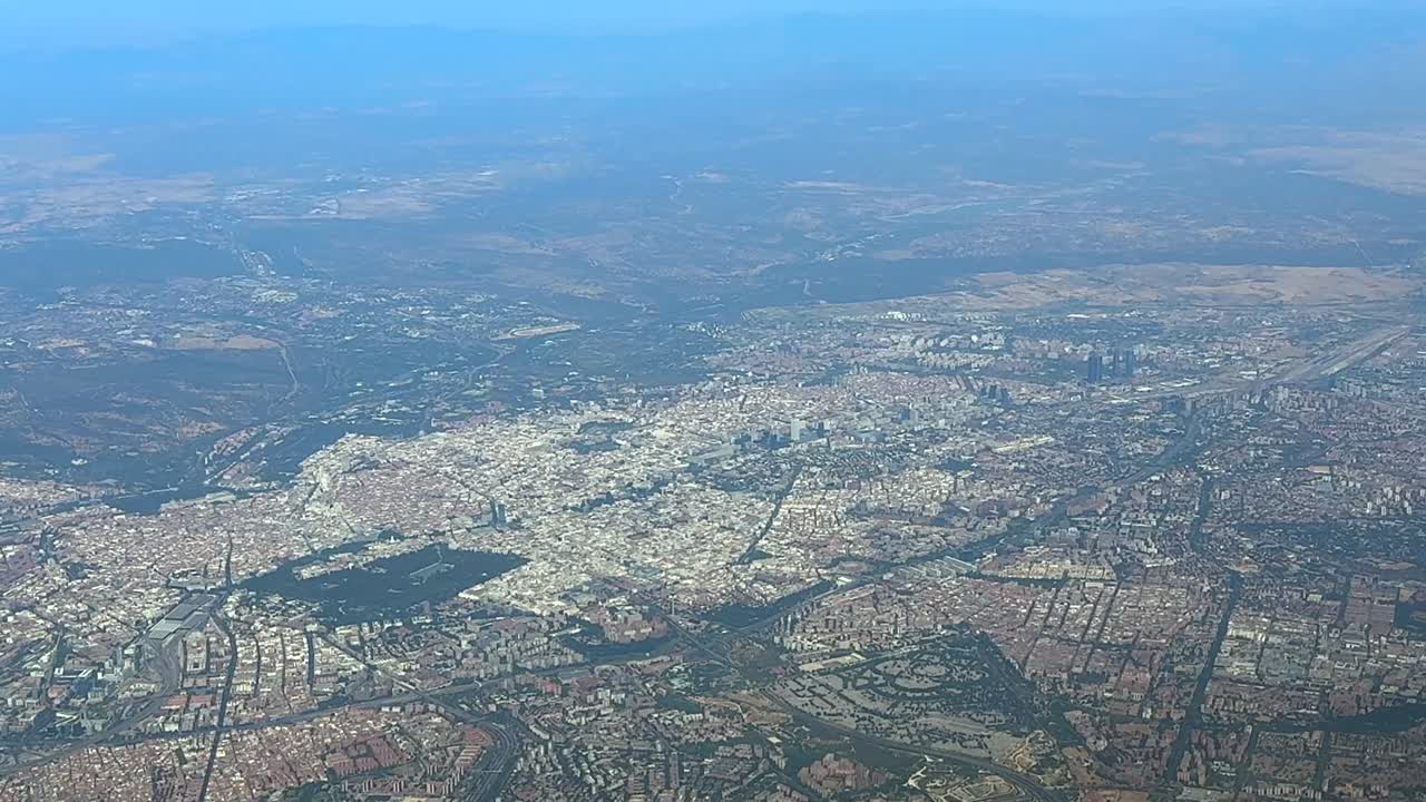 Al elevated aerial view of Madird city center and surroundings recorded from a plane cockpit in a hazy summer morning