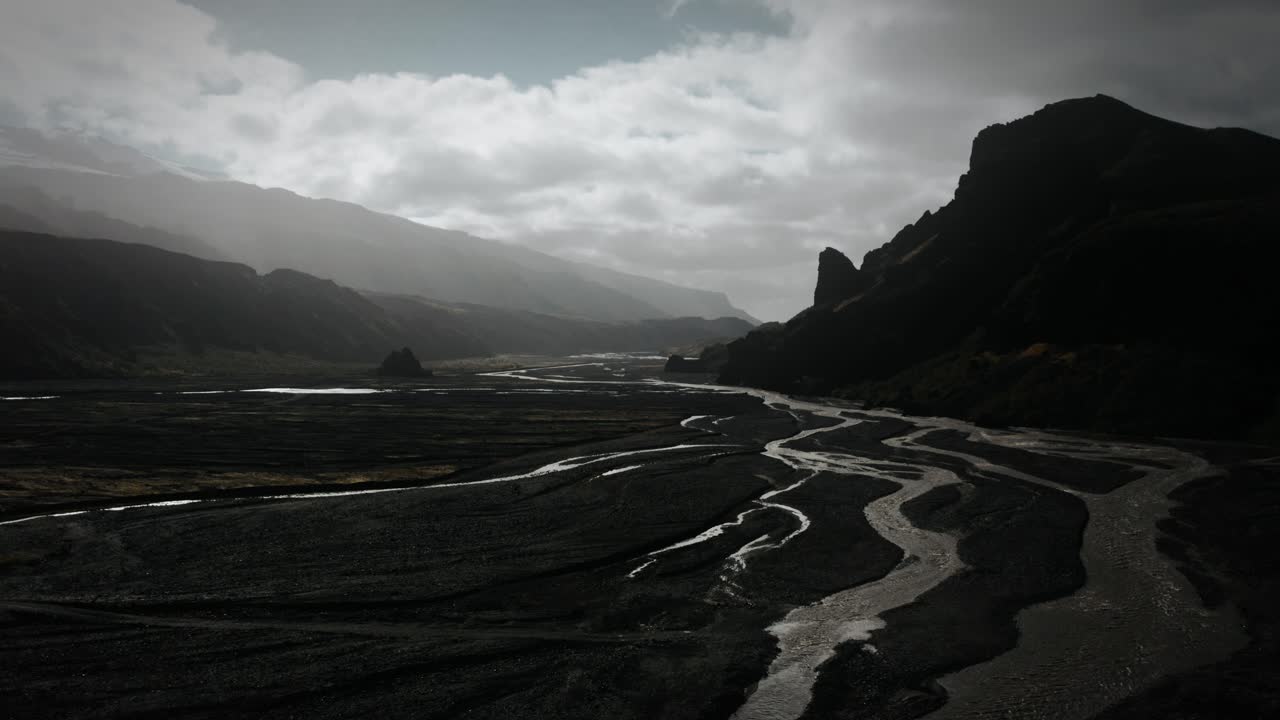 Dramatic aerial thor valley, glacial river flowing through black volcanic mountain, thorsm&ouml;rk national park Iceland