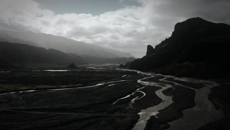 dramatic aerial thor valley, glacial river flowing through black volcanic mountain, thorsmörk national park iceland