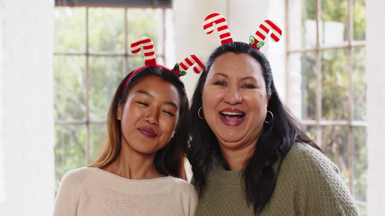 At christmas, Grandma and teenager wearing festive headbands, smiling joyfully at home