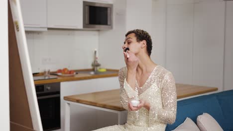 A-transgender-guy-in-fancy-dress-doing-make-up-with-brush-and-powder