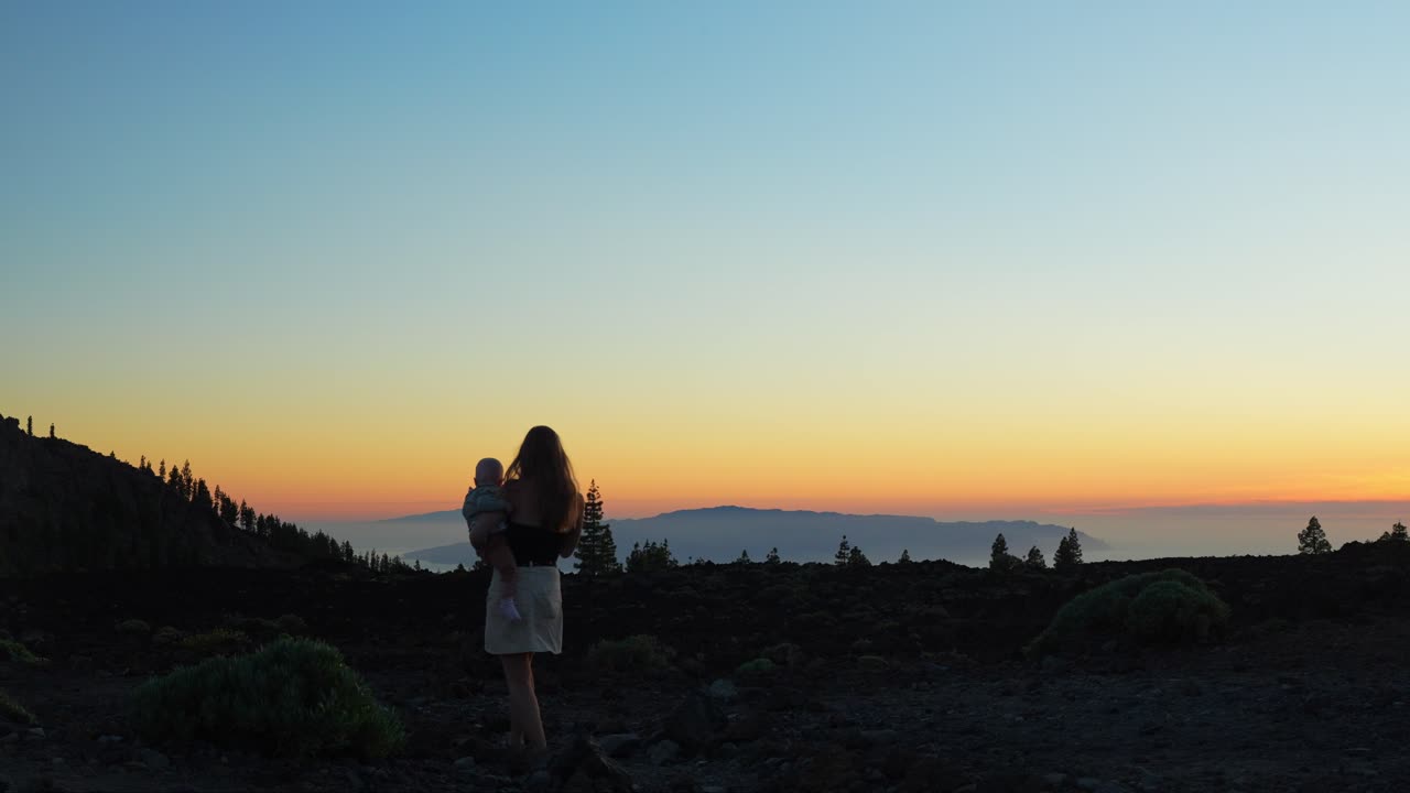 산에서 모험 하이킹, 배경에 해가 지는 하늘에 그녀의 손에 아기를 가진 여자