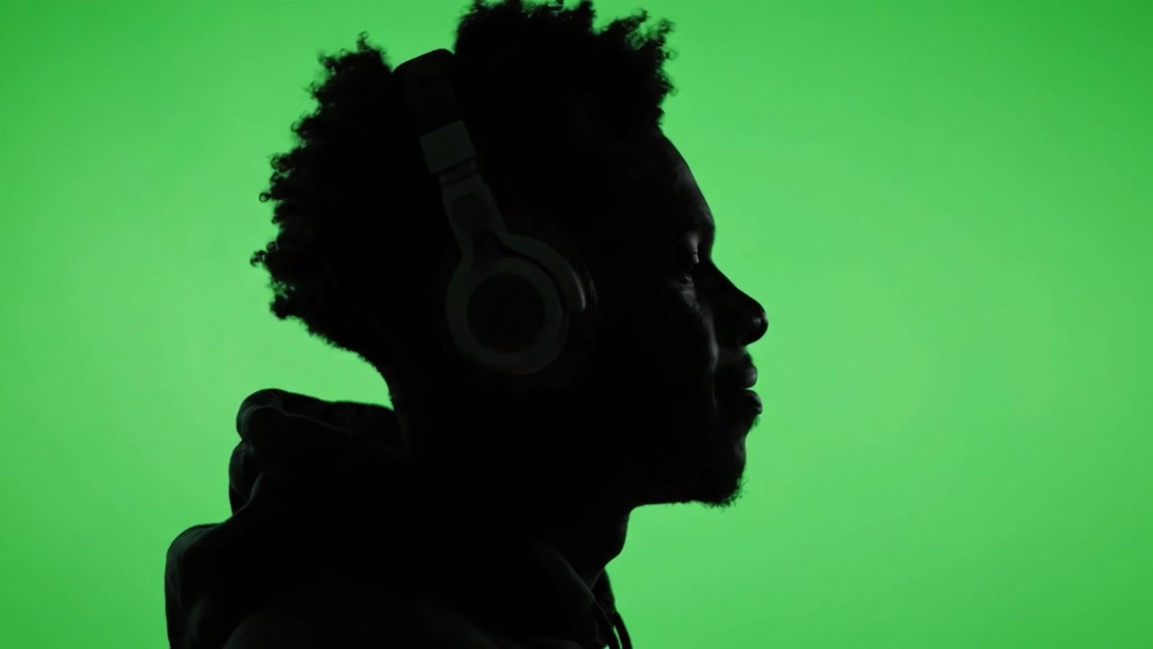 Esplorare le emozioni attraverso la musica: Il viaggio in silhouette di una persona con le cuffie, catturata su uno sfondo verde vibrante in momenti trasformativi.
