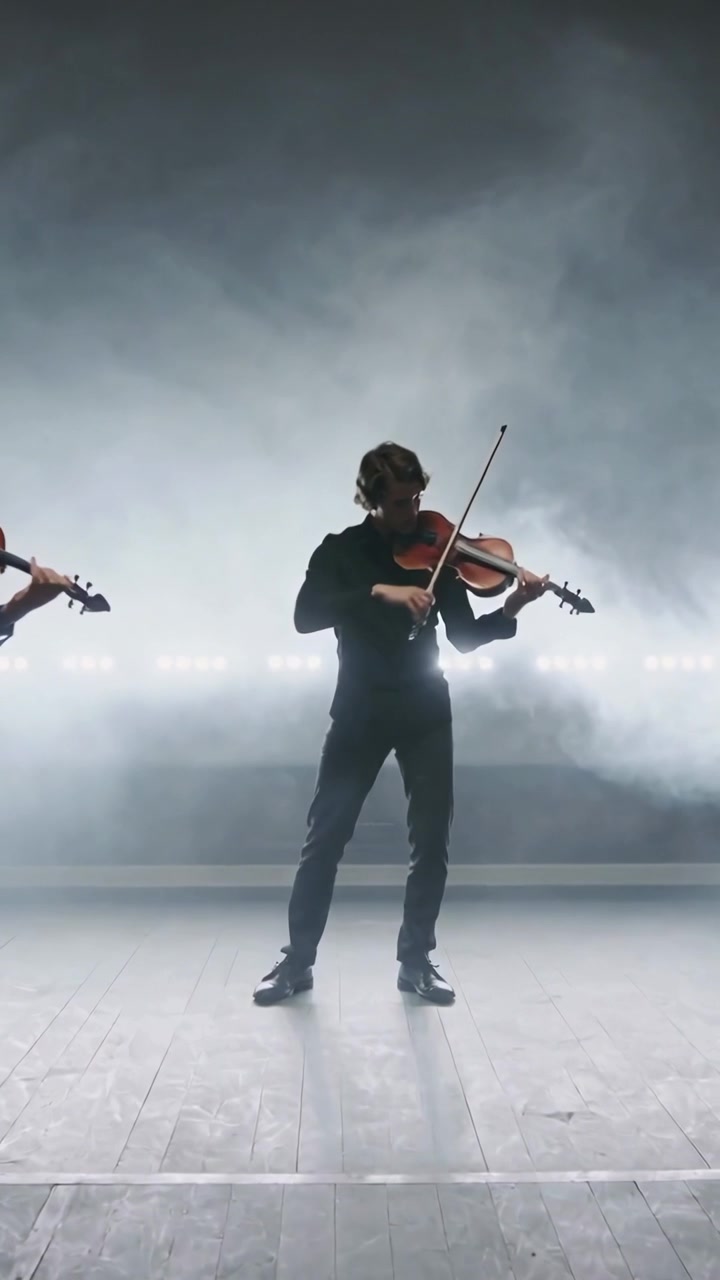 Lodret video: Reagerer på lyssignal, violinist i midten bukker på scenen i sort med violiner og tåge.
