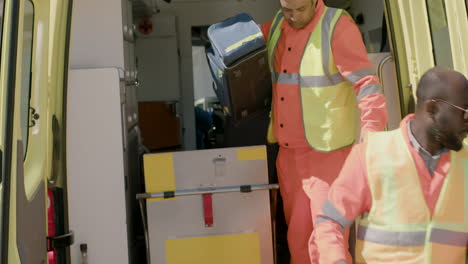 two paramedics opening the doors of the ambulance and taking medical equipment to attend a emergency