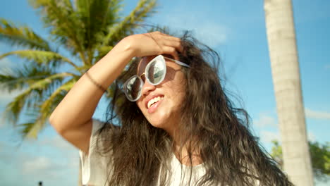 Hermosa-Chica-Filipina-Tropical-Arreglando-El-Cabello-Soplado-Por-El-Viento-Junto-A-Las-Palmeras