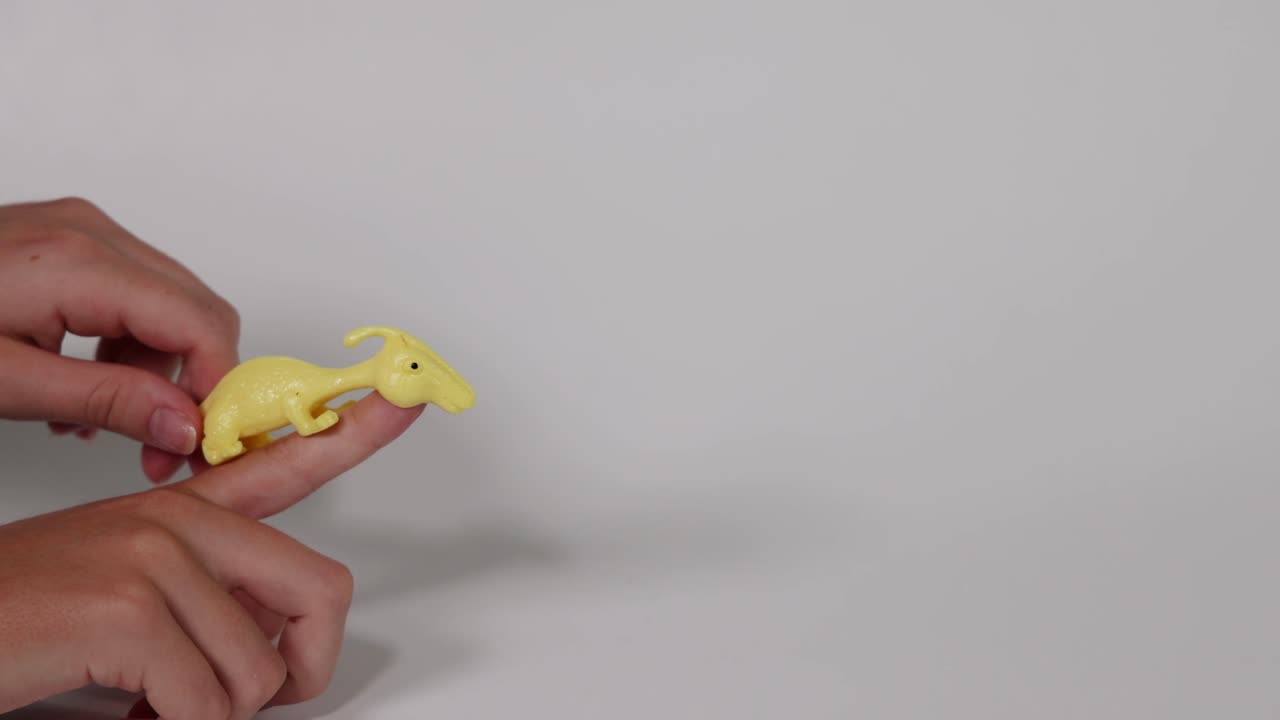 la mano lanza un juguete de dinosaurio amarillo hacia adelante