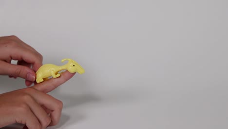 hand flings yellow dinosaur toy forward