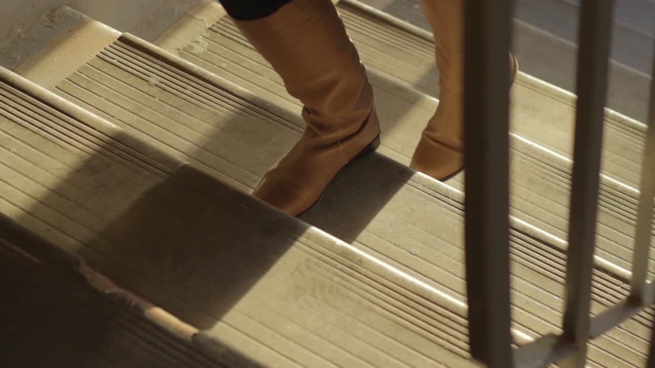 primer plano de ángulo alto de mujer botas zapatos subiendo escaleras, hora dorada luz del sol