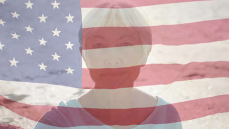 animation of american flag waving over portrait of senior woman on beach