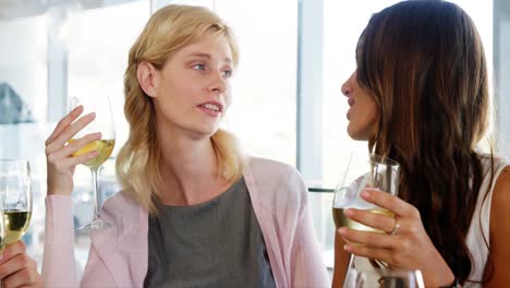 two omen holding their drink and speaking together