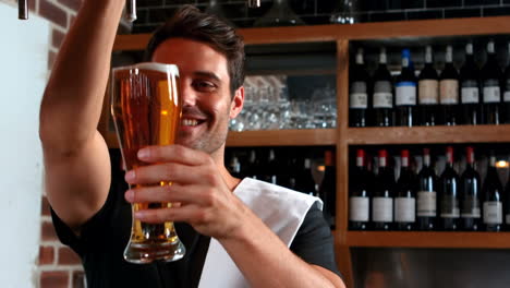 smiling barman pulling a pint of beer