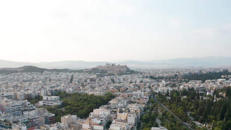 Aerial-shot-rising-up-from-the-ancient-city-of-Athens-to-see-Acropolis-on-a-distant-hill