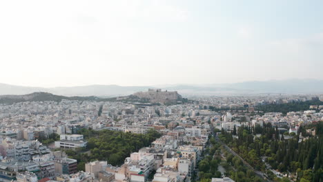 aerial shot rising up from the ancient city of athens to see acropolis on a distant hill